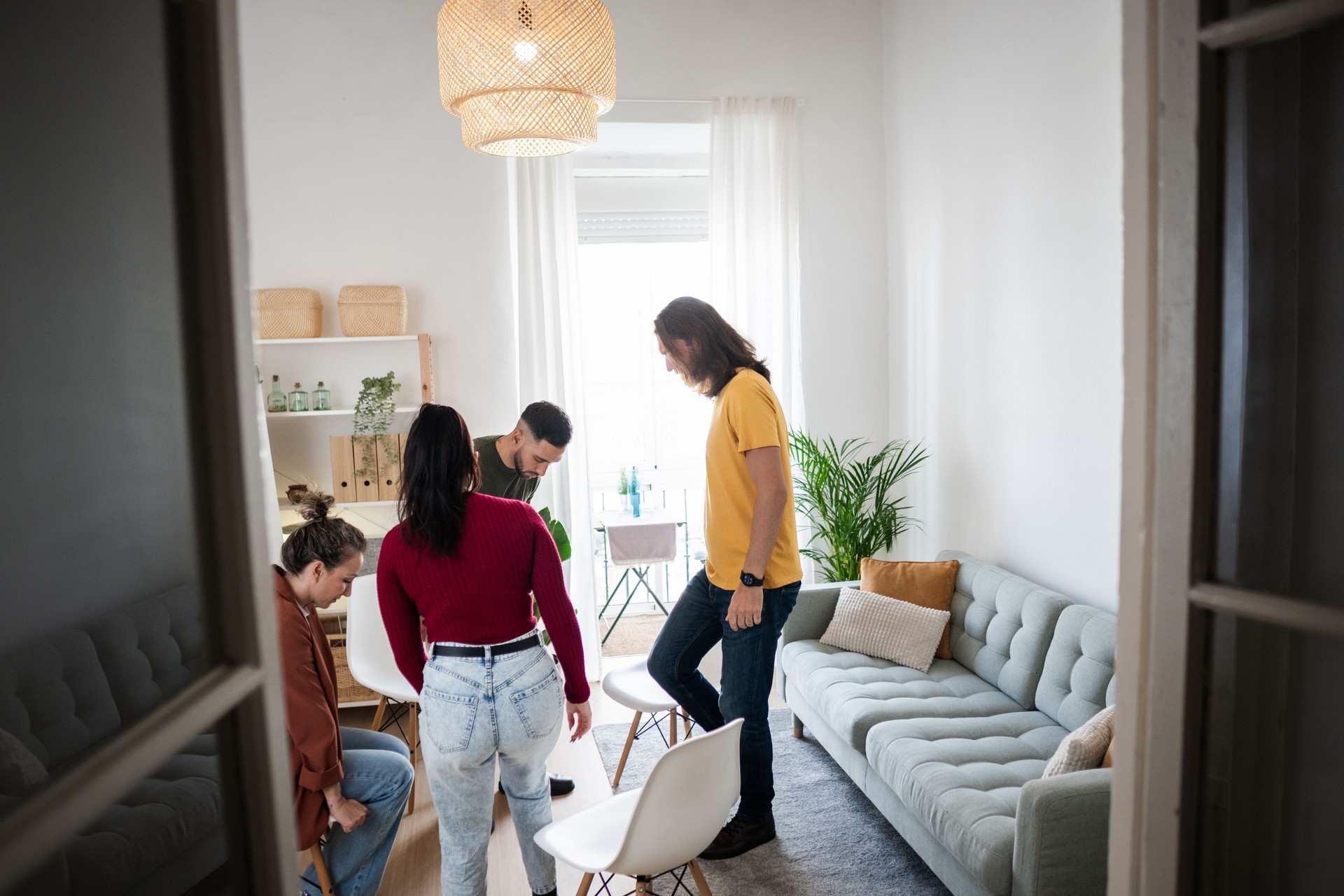 Young adults arranging chairs in modern apartment living room